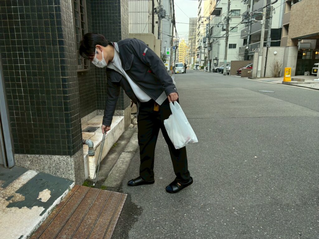 トングとゴミ袋を使用しゴミ拾いをする様子